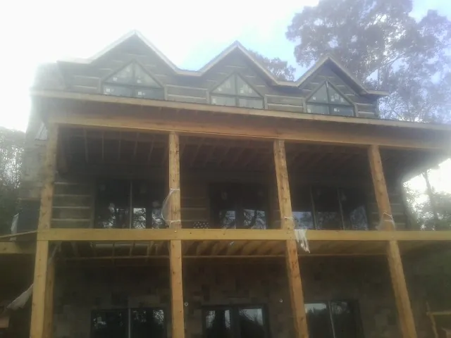 Dormers and porch framing on a large log home under construction — Roof Coating work by our crew in Randall